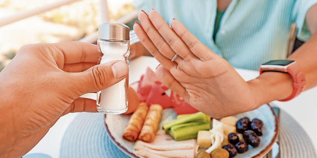 Woman in a restaurant refuses the offered salt and pepper shaker with a gesture of her hand. Diet for gout and high cardiovascular blood pressure