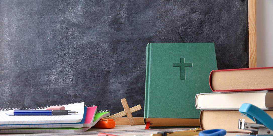 Religion class with desk with tools, Bible and blackboard