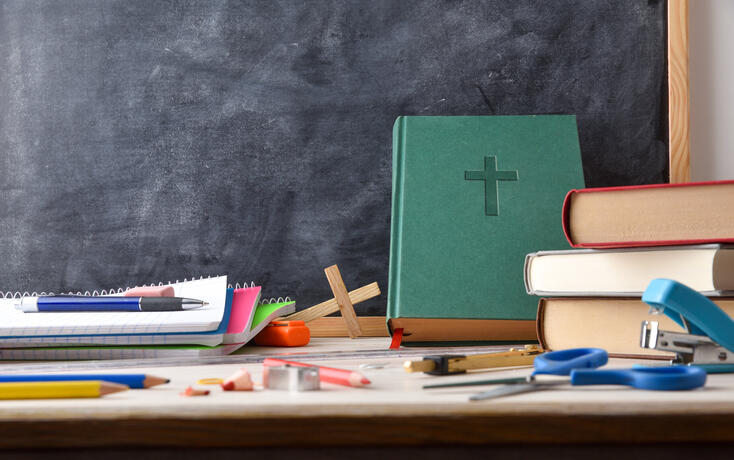 Religion class with desk with tools, Bible and blackboard