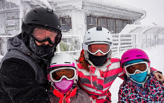 Family on winter vacations taking selfie on mountain slope.