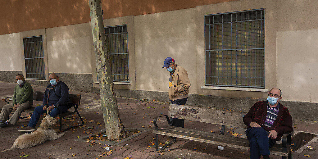 Ältere Menschen sitzen in einem Park in Vallecas, einem ärmeren Madrider Viertel, das teilweise abgeriegelt ist. Foto: Bernat Armangue/AP/dpa