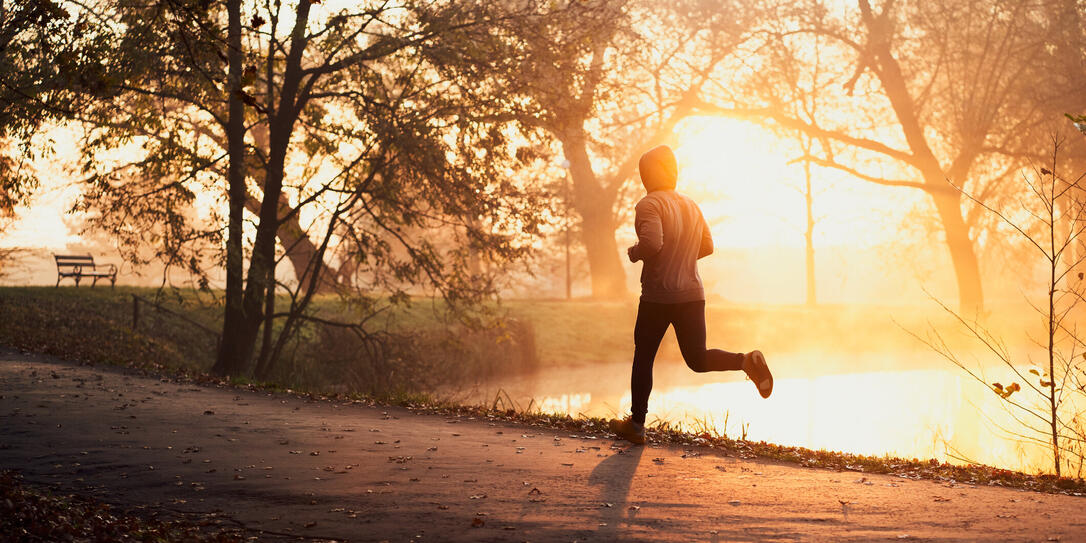 Active man jogging in park during autumn sunny morning