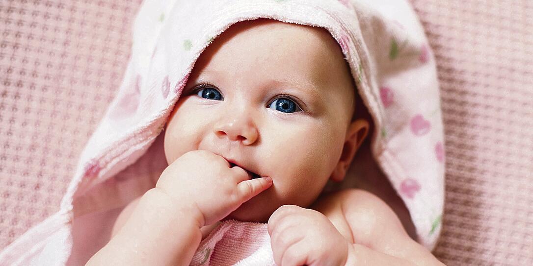 Authentic portrait of 4 months baby girl wrapped in towel after bath.