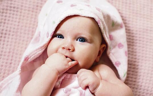 Authentic portrait of 4 months baby girl wrapped in towel after bath.