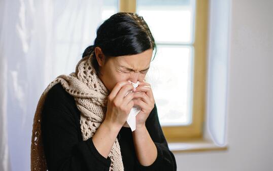 YOUNG WOMAN BLOWING HER NOSE