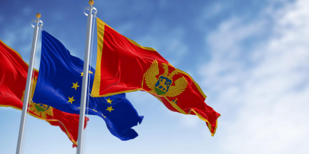 Montenegro and European Union flags waving in the wind on a clear day