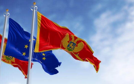 Montenegro and European Union flags waving in the wind on a clear day
