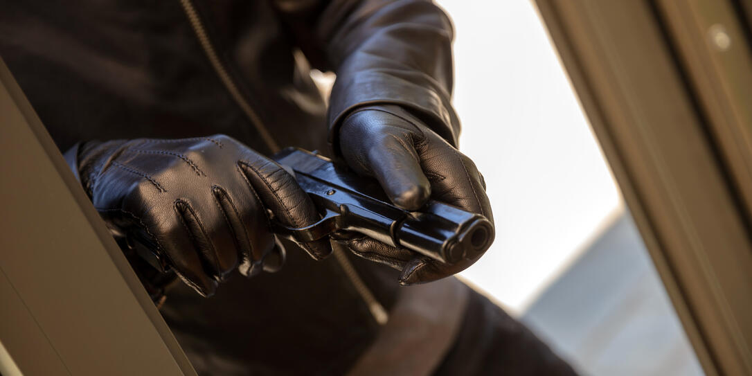 Armed man in a leather jacket holding a pistol closeup view
