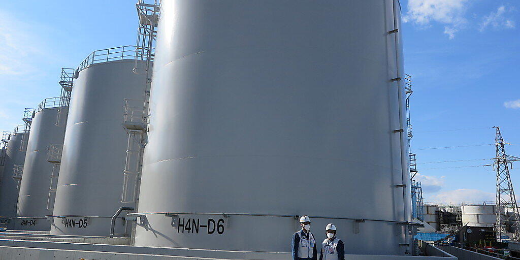 ARCHIV - Mitarbeiter des Betreiberkonzerns Tepco stehen vor riesigen Tanks, in denen verstrahltes Wasser, das bei der andauernden K&uuml;hlung der besch&auml;digten Reaktoren von Fukushima anf&auml;llt, gelagert wird. Inzwischen haben sich 1,1 Millionen Tonnen angeh&auml;uft, langsam geht der Platz f&uuml;r weitere Tanks aus. Foto: Lars Nicolaysen/dpa