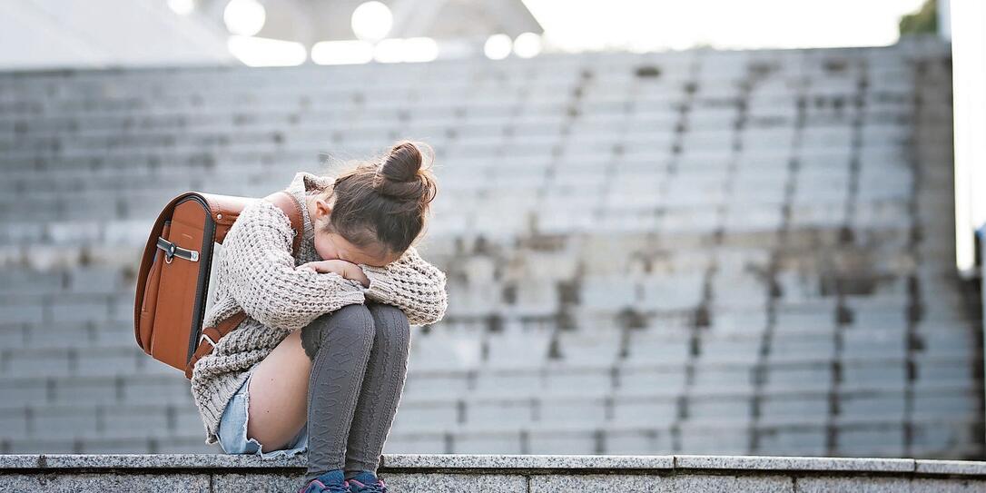 Elementary school students sitting on the steps and crying