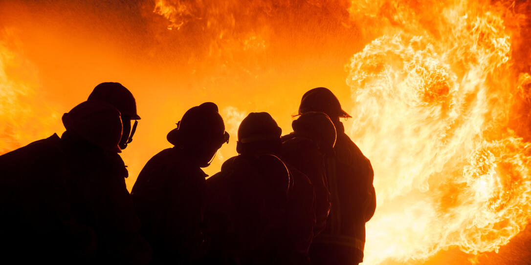 Silhouette of Firemen fighting a raging fire