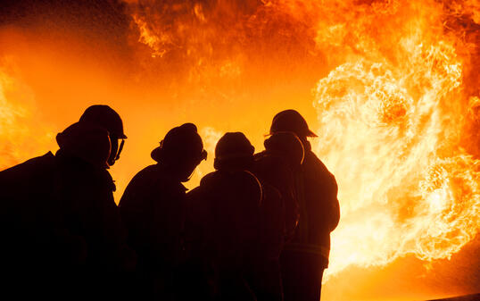 Silhouette of Firemen fighting a raging fire