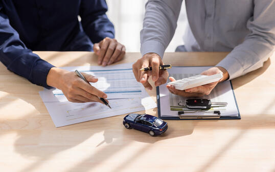 Dealer salesman giving car key to owner. client signing insurance document or rental car lease form agreement contract Insurance car concept.