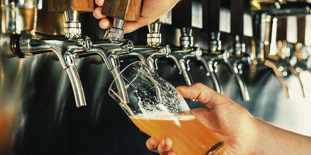Hand of bartender pouring a large lager beer in tap Hand of bartender pouring a large lager beer in tap