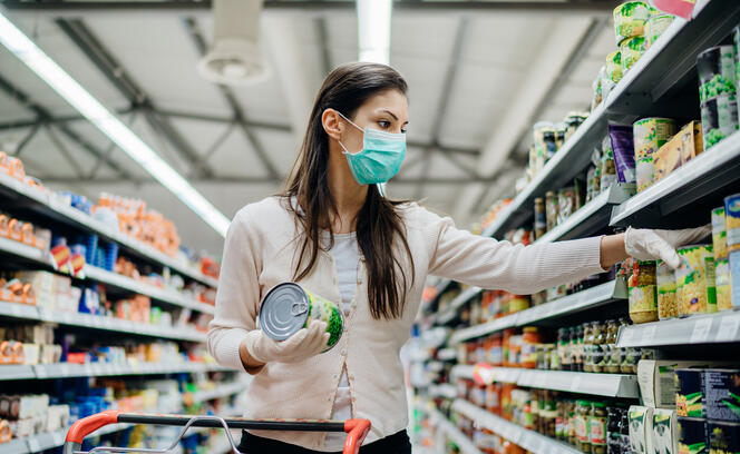 Woman preparing for pathogen virus pandemic spread quarantine.Choosing nonperishable food essentials.Budget buying at a supply store.Pandemic quarantine preparation.Emergency to buy list