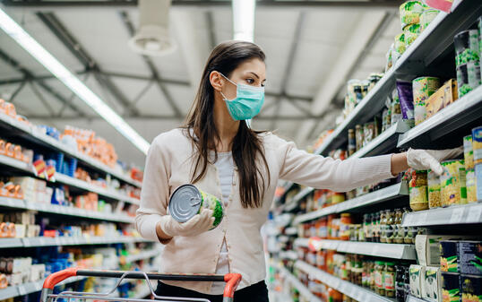 Woman preparing for pathogen virus pandemic spread quarantine.Choosing nonperishable food essentials.Budget buying at a supply store.Pandemic quarantine preparation.Emergency to buy list