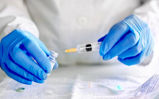 Doctor fills injection syringe with vaccine