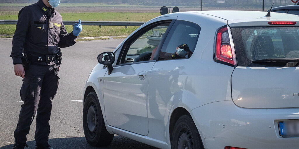 Ein Polizist stoppt ein Auto beim Ort Casalpusterlengo, der wegen des Coronavirus abgeriegelt ist. Ein Polizist stoppt ein Auto beim Ort Casalpusterlengo, der wegen des Coronavirus abgeriegelt ist.