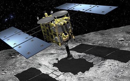 Hayabusa2 beim Sammeln von Gesteinsproben auf dem Asteroiden Ryugu. Die Arbeit ist getan, am Samstag wirft Hayabusa ihr Sammelkörbchen im Vorbeifliegen an der Erde ab, um gleich wieder zur nächsten Mission weiter zu ziehen. (JAXA)
