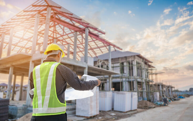 Professional engineer architect worker with protective helmet and blueprints paper at house building construction site
