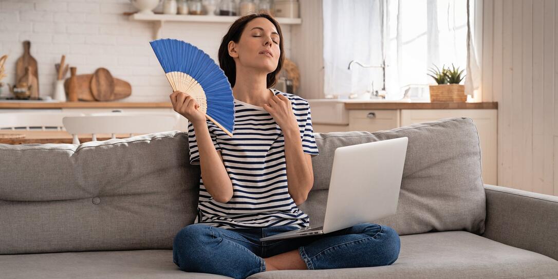 Young woman suffers from heatstroke flat without air-conditioner waving fan sitting on couch at home Young woman suffers from heatstroke flat without air-conditioner waving fan sitting on couch at home