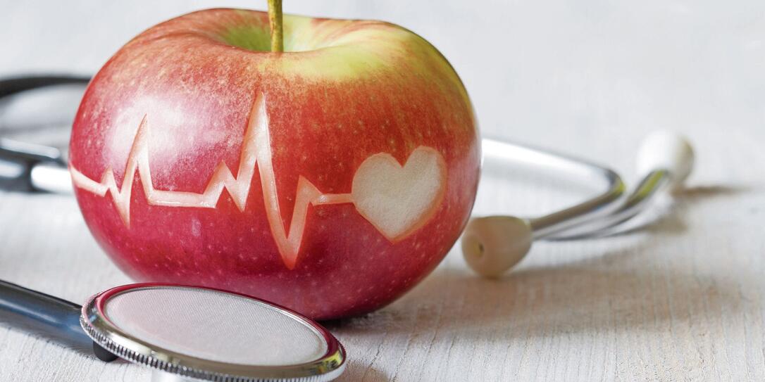 Heartbeat line on red apple and stethoscope, healthy heart diet concept