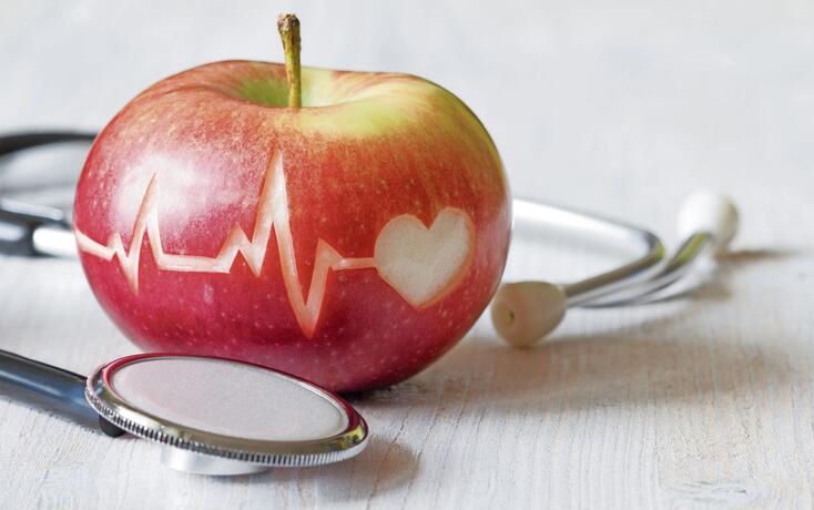 Heartbeat line on red apple and stethoscope, healthy heart diet concept