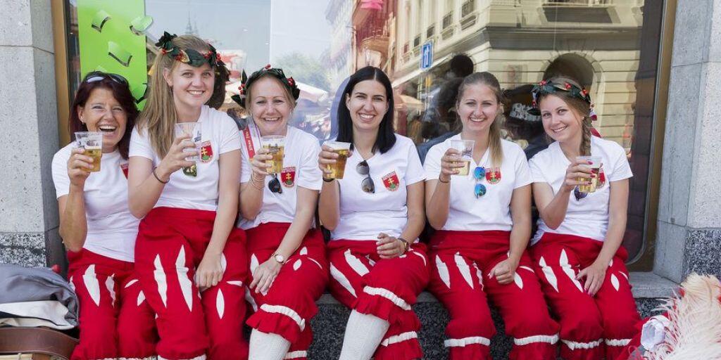 Junge Tambour- und Piccolo-Spielerinnen erfrischen sich am Tambouren- und Pfeiferfest in Bulle bei hochsommerlichen Temperaturen vor dem grossen Abschluss-Umzug.