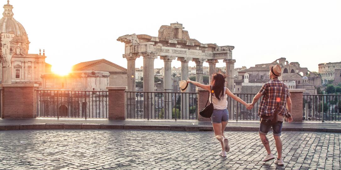 Young couple tourist walking pointing towards Roman Forum at sunrise. Historical imperial Foro Romano in Rome, Italy from panoramic point of view. Young couple tourist walking pointing towards Roman Forum at sunrise. Historical imperial Foro Romano in Rome, Italy from panoramic point of view.
