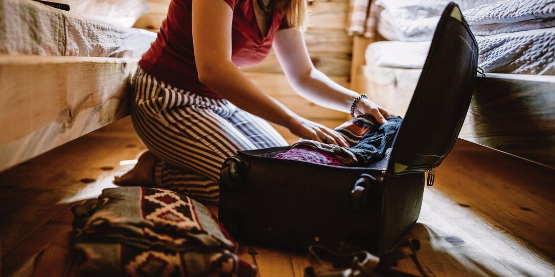 Unrecognizable woman packing luggage in log cabin