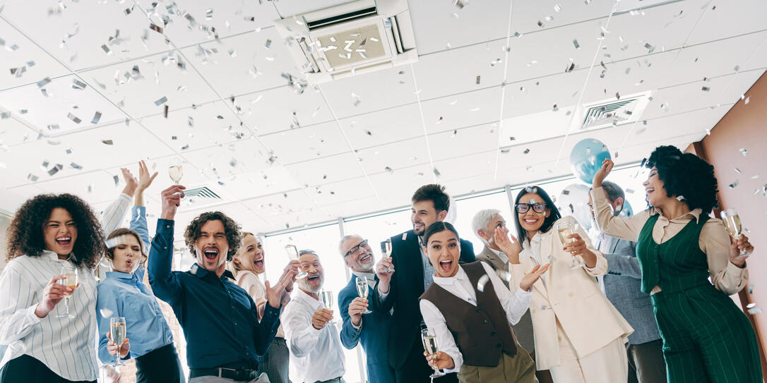 Diverse business team celebrates success indoors with confetti and champagne in an inclusive and dynamic office environment