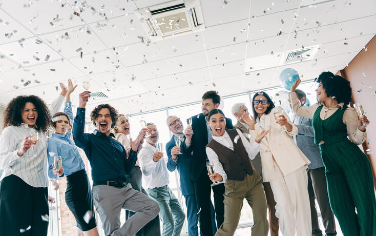 Diverse business team celebrates success indoors with confetti and champagne in an inclusive and dynamic office environment