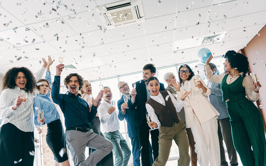 Diverse business team celebrates success indoors with confetti and champagne in an inclusive and dynamic office environment