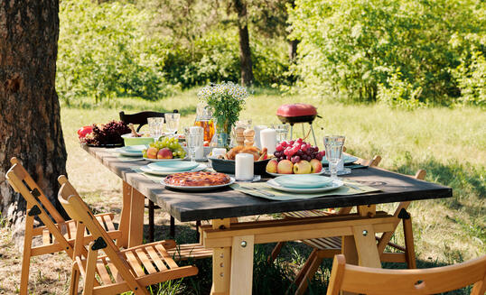 Group of chairs surrounding wooden served festive table with homemade food