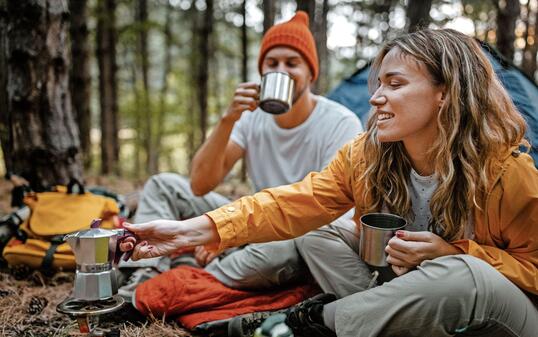 Young couple making coffee during hiking