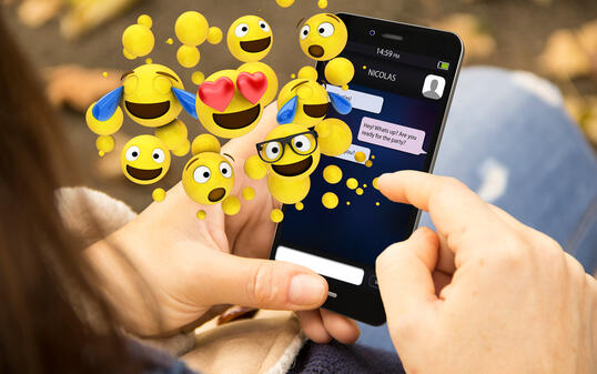 woman sending emoticons with the phone at the park