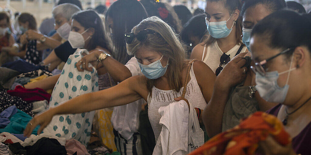 Kundinnen, die Mundschutz tragen, kaufen Kleidung an einem Stand auf einem Markt in Barcelona. Die spanische Region Katalonien führt eine ungewöhnlich strenge Maskenpflicht ein. Foto: Emilio Morenatti/AP/dpa