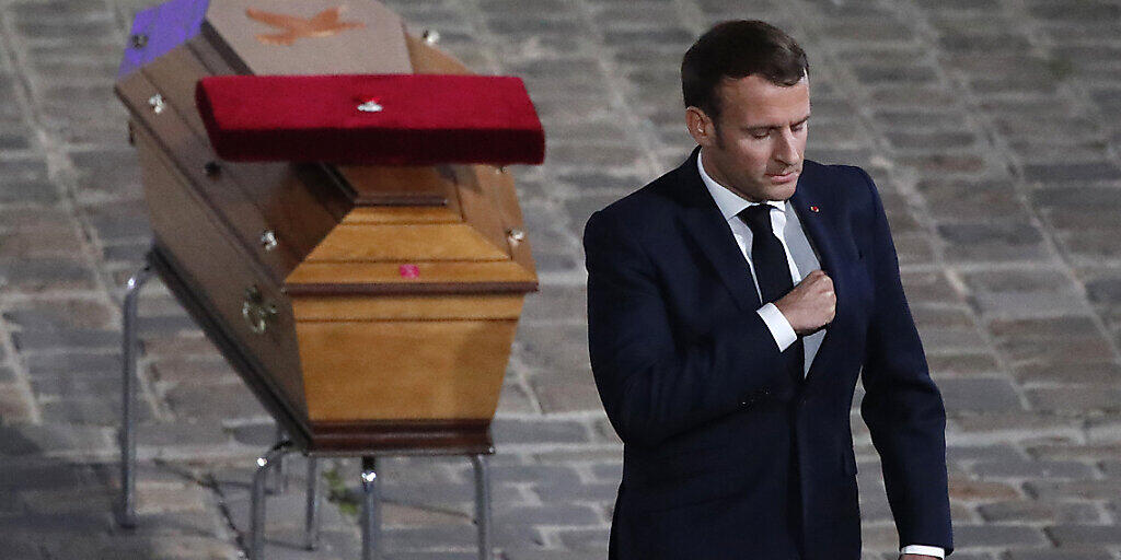 Der französische Staatspräsident Emmanuel Macron wendet sich bei der Gedenkveranstaltung für Samuel Paty vom Sarg des ermordeten Lehrers ab. Foto: Francois Mori/AP/dpa