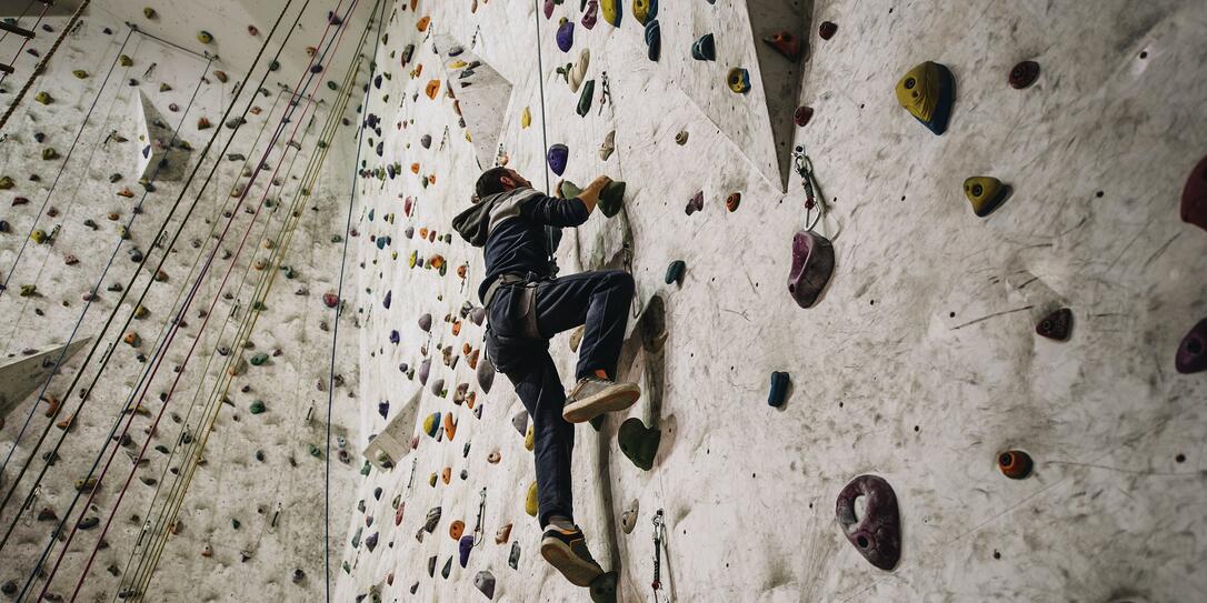 Low angle view of athletic man climbing on the wall in a gym.