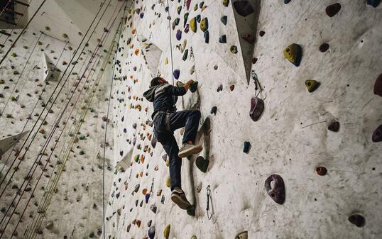 Low angle view of athletic man climbing on the wall in a gym.