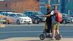 A young man and a girl on the same electric scooter at the intersection