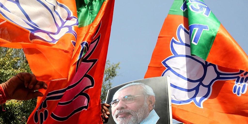 Anhänger von Indiens Regierungschef Narendra Modi feiern mit Fahnen und Modi-Bild ihren Wahlsieg in Uttar Pradesh