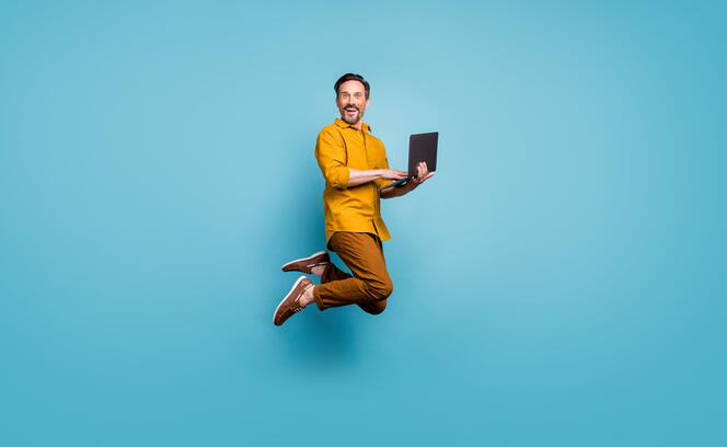 Full size photo of funky man feel rejoice emotions jump use laptop search social media online black friday discounts wear casual style clothing isolated over blue color background
