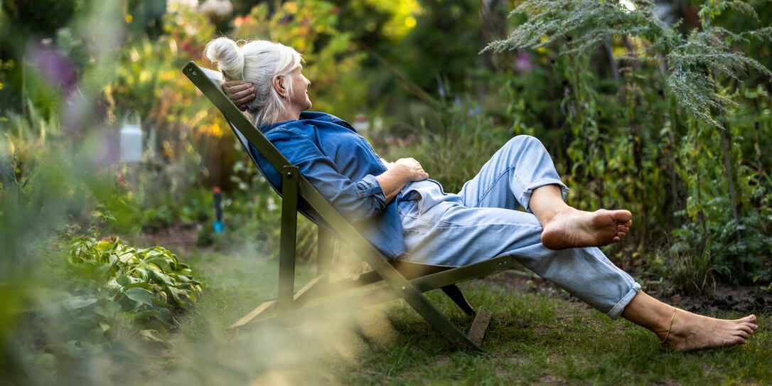 Mature woman relaxing in deckchair in her garden