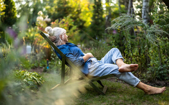 Mature woman relaxing in deckchair in her garden
