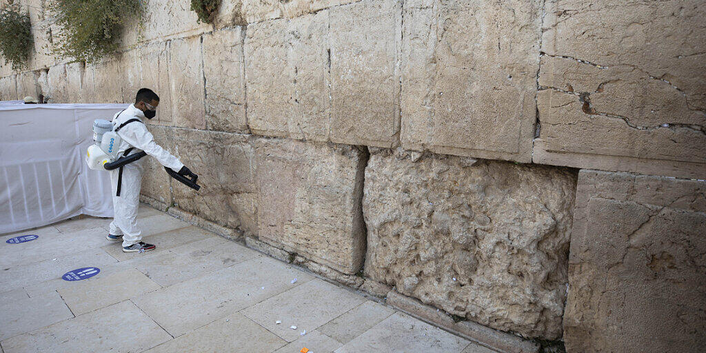 dpatopbilder - Ein Arbeiter verteilt Desinfektionsmittel als Vorsichtsmaßnahme gegen das Coronavirus an der Westmauer, der heiligsten Stätte, an der Juden in Jerusalem beten können. Foto: Sebastian Scheiner/AP/dpa