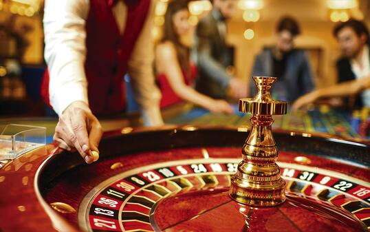The croupier holds a roulette ball in a casino in his hand.