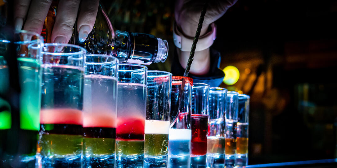 woman bartender hand making collection of colorful shots. Set of cocktails at the bar counter