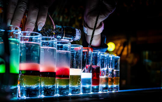 woman bartender hand making collection of colorful shots. Set of cocktails at the bar counter