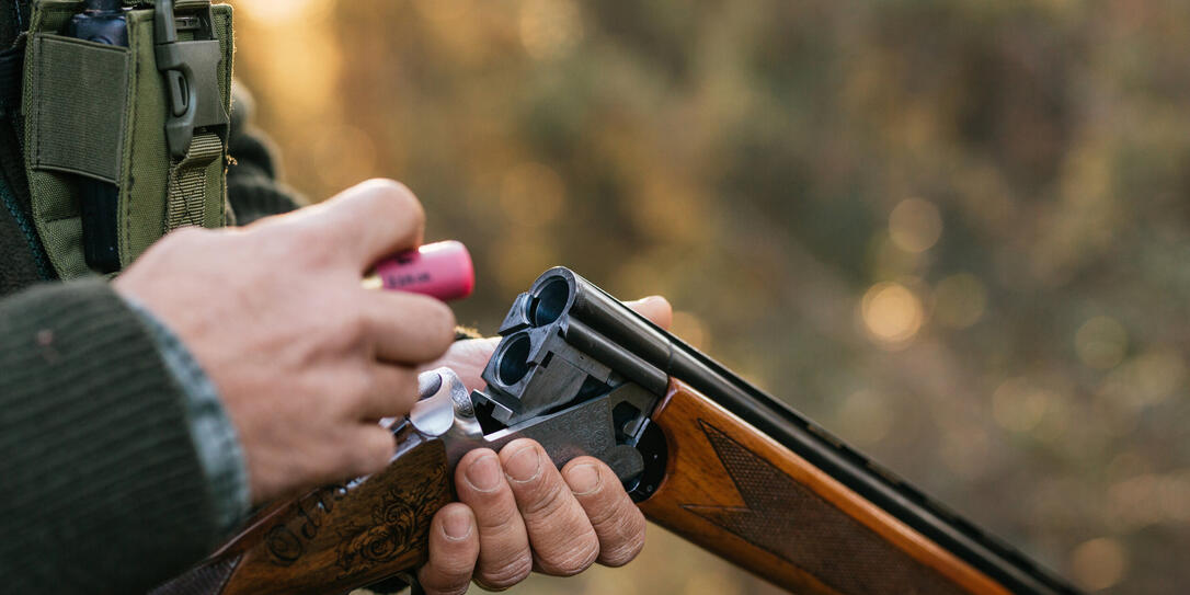 Hunter man loading his gun while hunting outdoors.